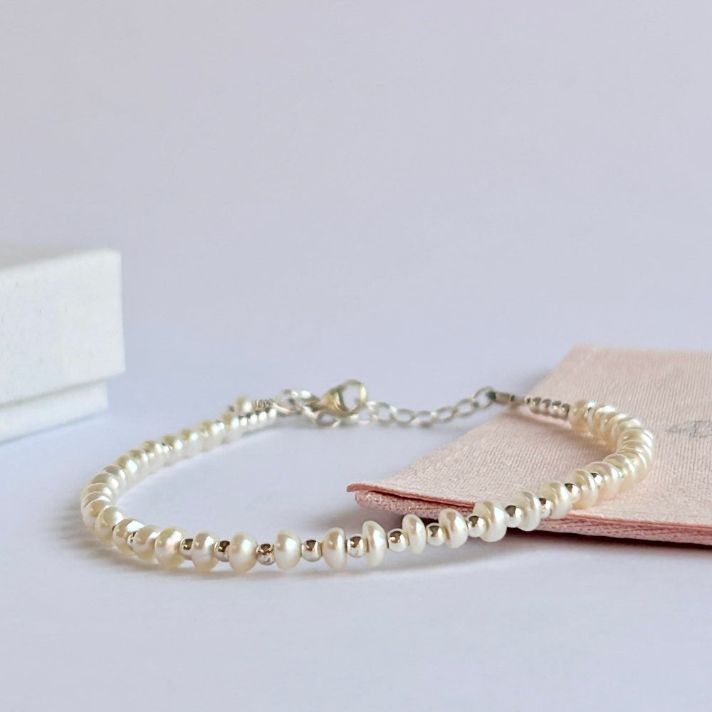 Button Pearl bracelet on a light pink jewellery pouch and a light coloured background.