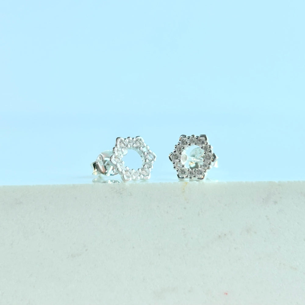 A pair of silver hexagon stud earrings with sparkling cubic zirconia stones set in a floral-like pattern, displayed against a light background.