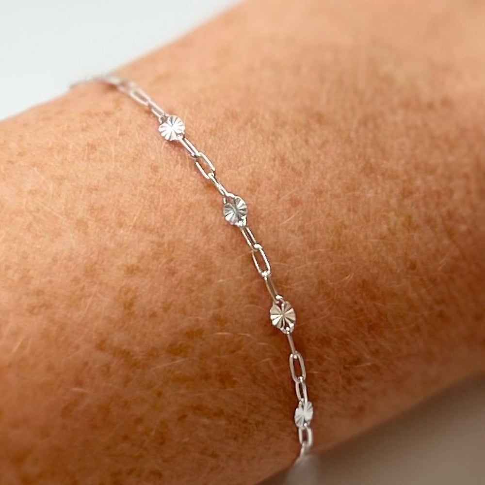 Close up of sterling silver starburst bracelet on a wrist against a neutral background