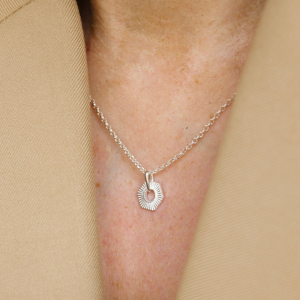 Sterling silver Hexagon necklace on a person's neck against a beige background
