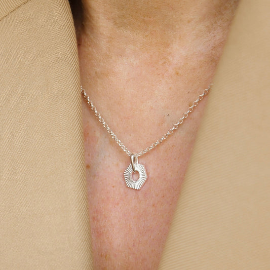 Sterling silver Hexagon necklace on a person's neck against a beige background