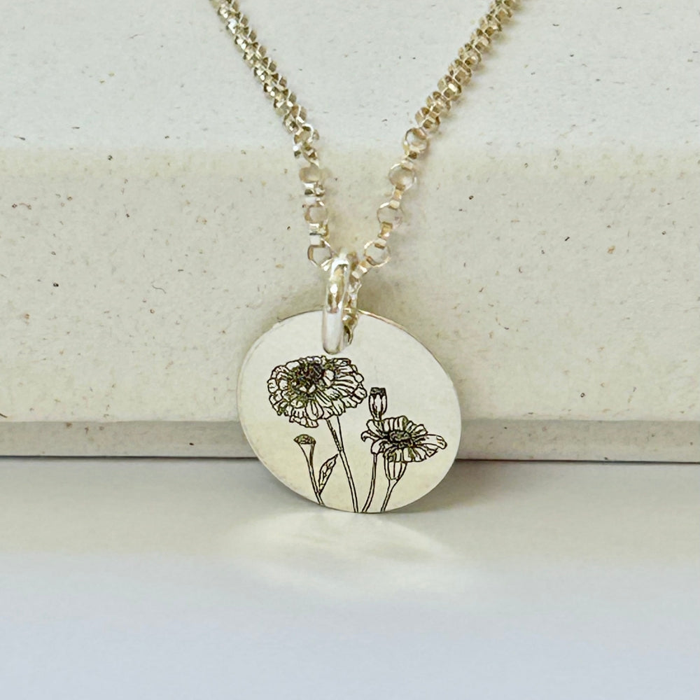 Sterling silver necklace with a round pendant featuring floral design on a light background