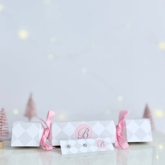 Cracker gift box tied with pink ribbons and silver snow flake stud earrings in the foreground.