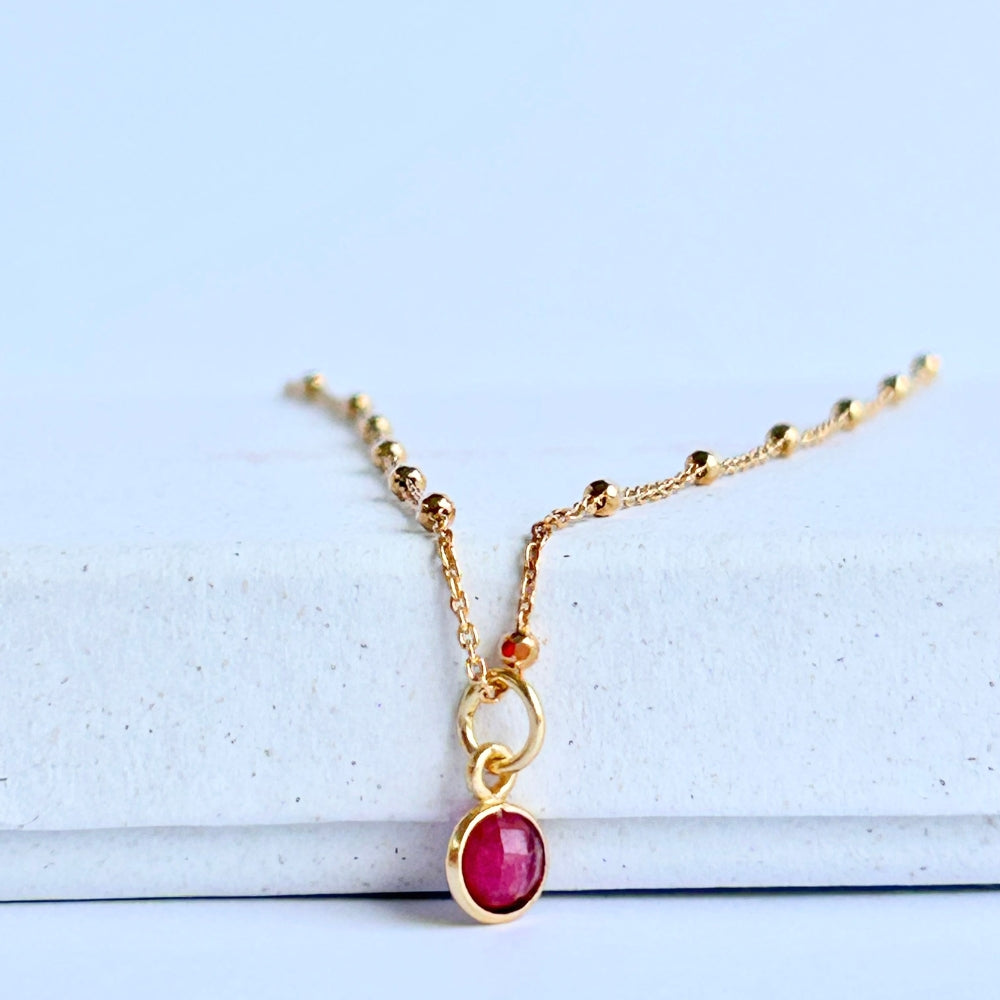 Gold necklace with a tuby pendant resting on a white box